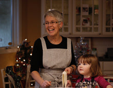 Load image into Gallery viewer, Grandmother baking in indigo striped Hovden Wear apron. Her granddaughter is next to her.
